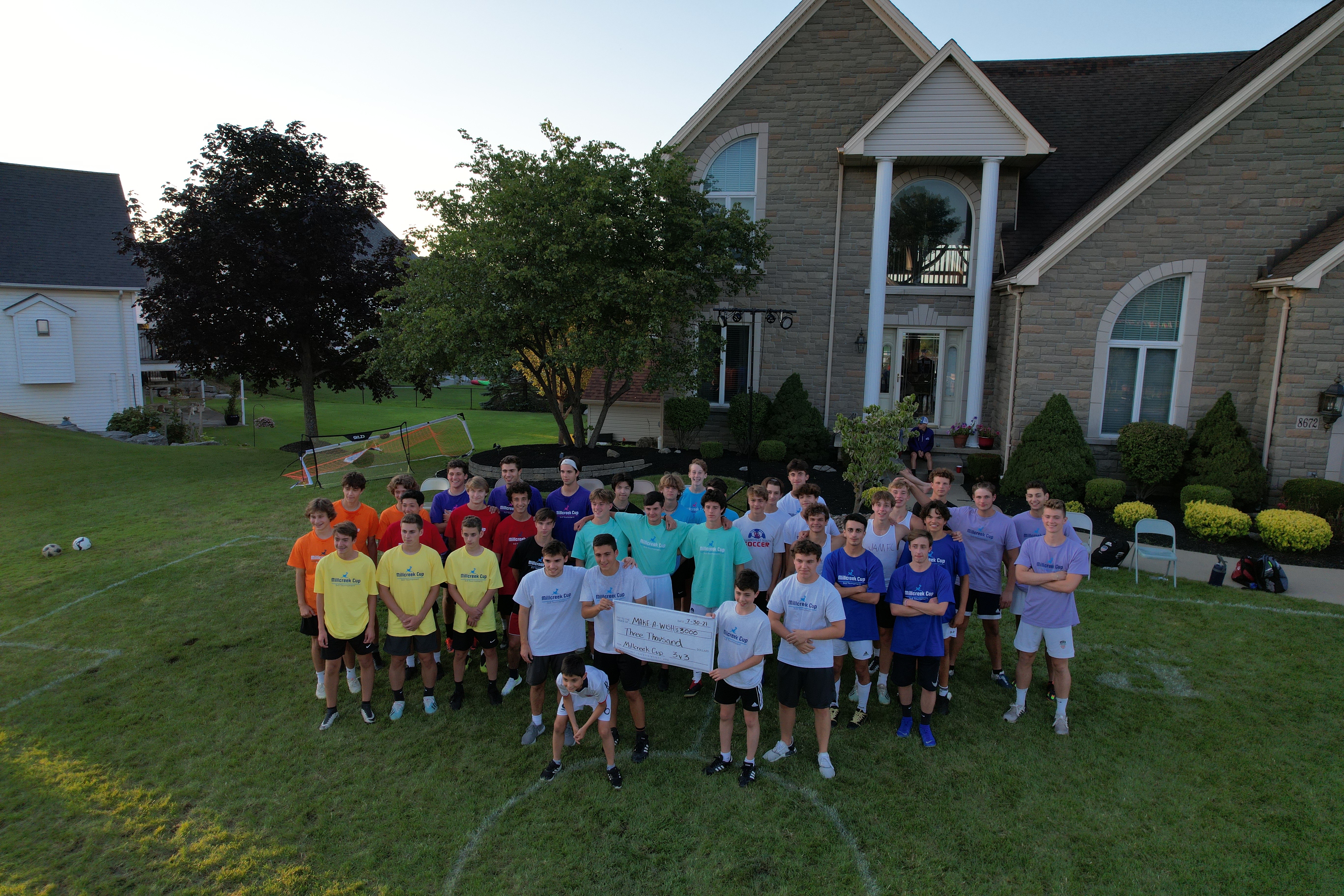 Millcreek Cup players holding a $3,000 Make-A-Wish donation check